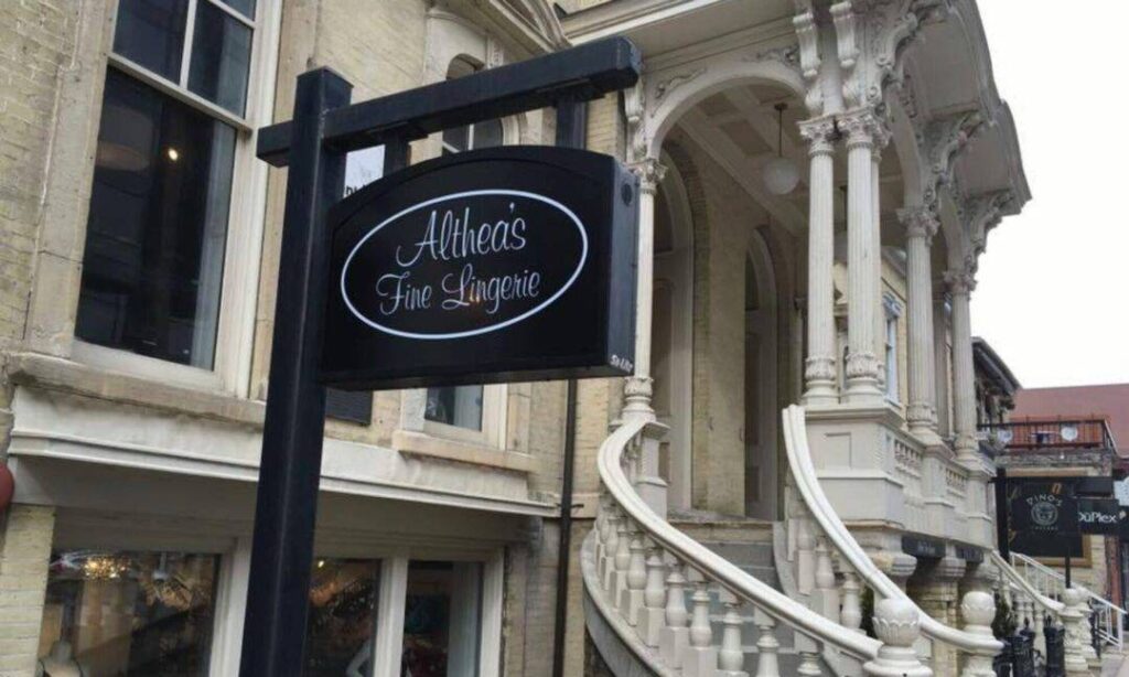 altheas-fine-lingerie-storefront-milwaukee » milwaukeelingerie.com Exterior view of Althea’s Fine Lingerie in Milwaukee, featuring its black oval shop sign and historic cream city brick facade.