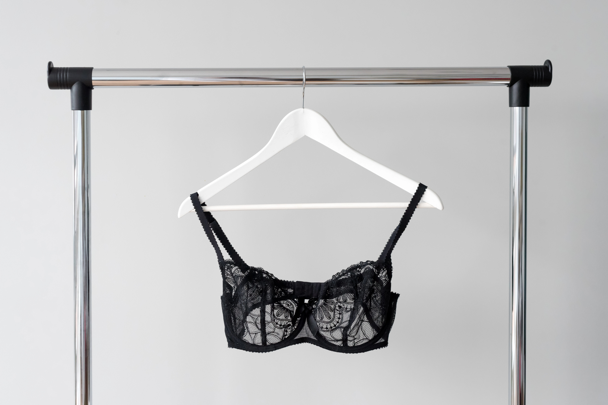 Black lace bra on a white hanger, styled on a chrome rack—minimalist image for a Milwaukee lingerie and bra fitting guide.