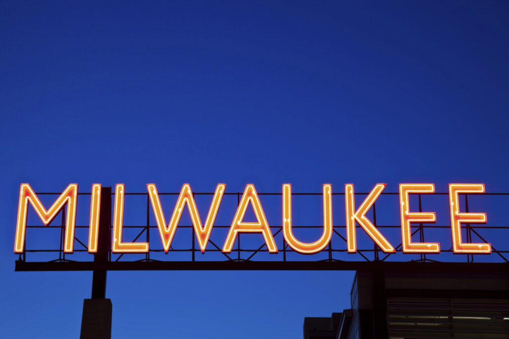 milwaukee neon sign night skyline » milwaukeelingerie.com Bright neon Milwaukee sign glowing against a deep blue night sky—used to anchor local identity and pride on a Milwaukee lifestyle website.